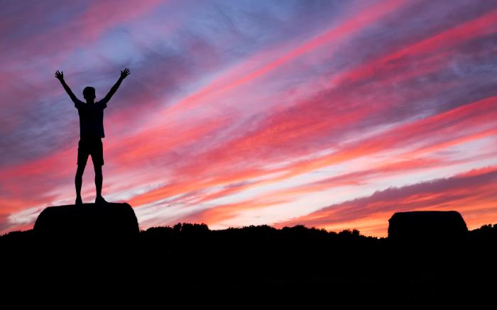 silhouette of man standing on high ground under red and blue skies by Benjamin Davies courtesy of Unsplash.