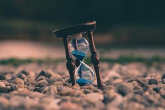 selective focus photo of brown and blue hourglass on stones by Aron Visuals courtesy of Unsplash.