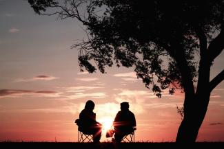 silhouette of two person sitting on chair near tree by Harli Marten courtesy of Unsplash.